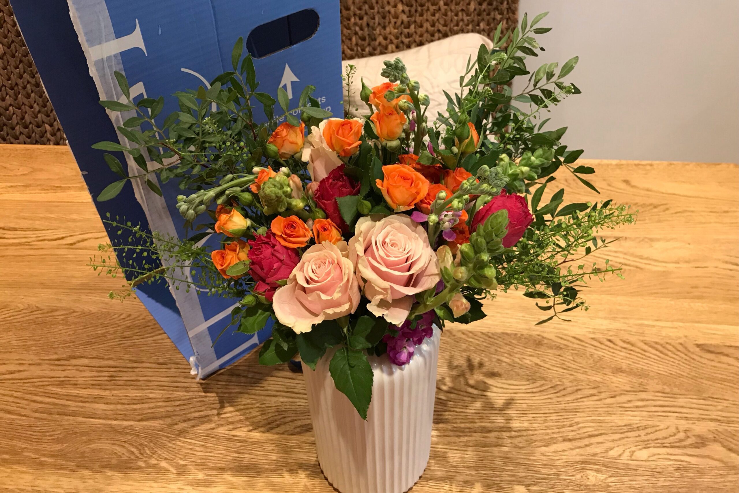 Arena Flowers delivery bouquet and box on a wooden table