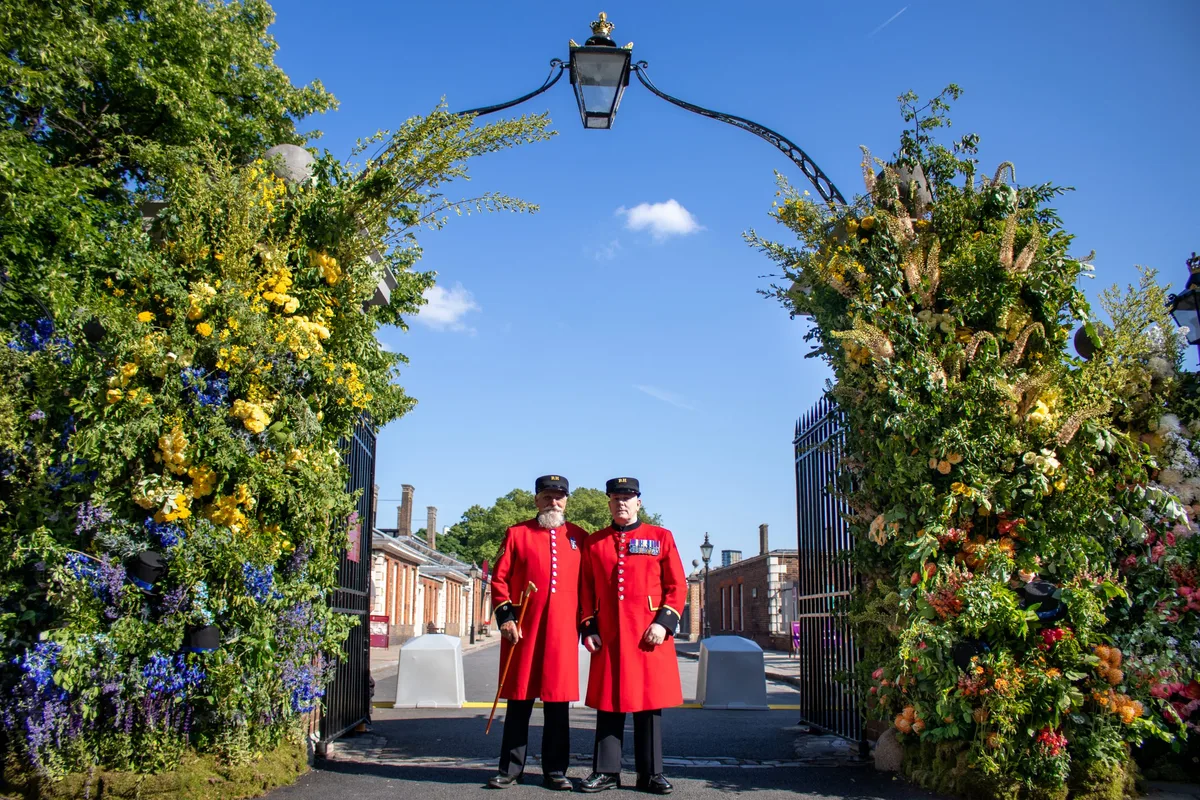 RHS Chelsea Flower Show - Chelsea Pensioners outside Lavender Green Flowers London Gate Installation The entry gates to RHS Chelsea Flower Show 2025 with floral design created by Lavender Green