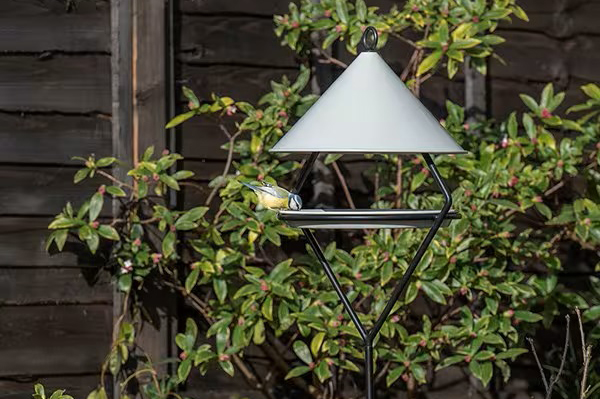 Bird feeding hut on stake in a garden