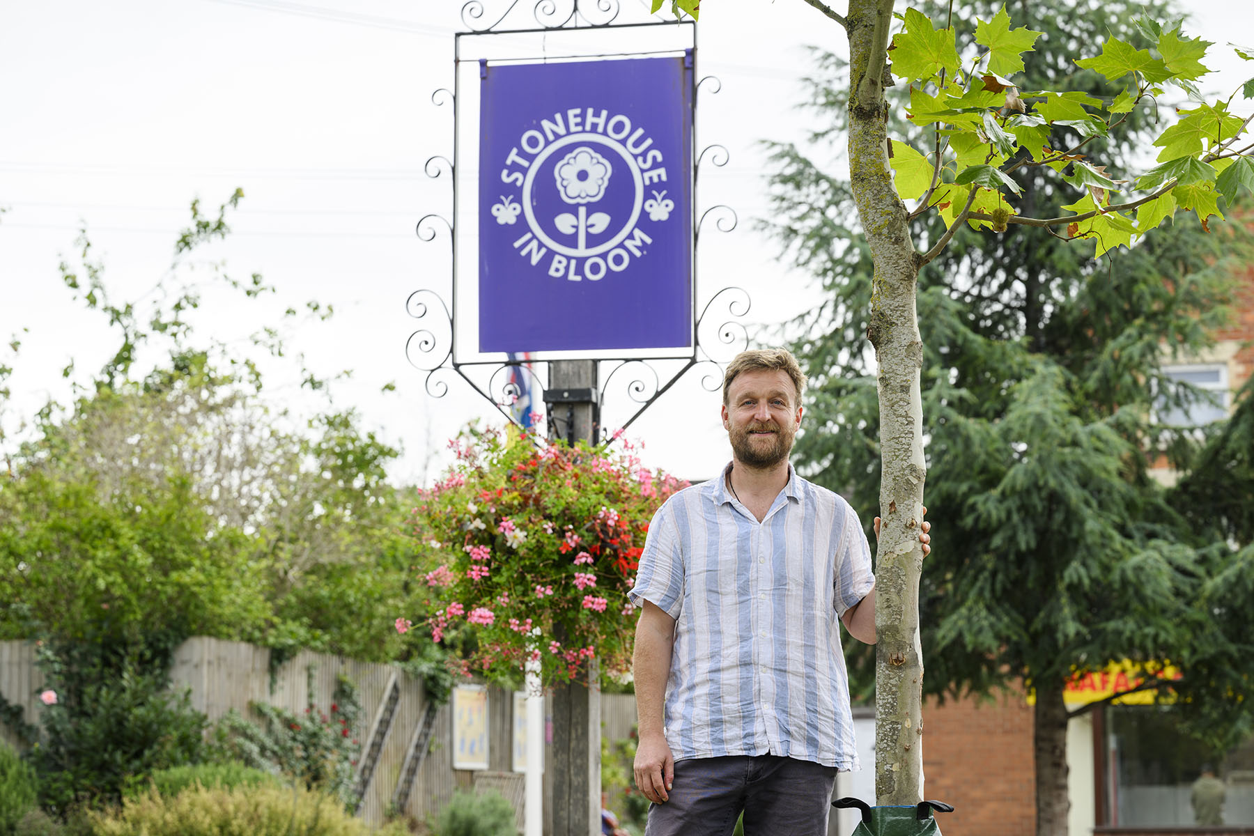 Man standing in front of RHS Stonehouse in Bloom sign