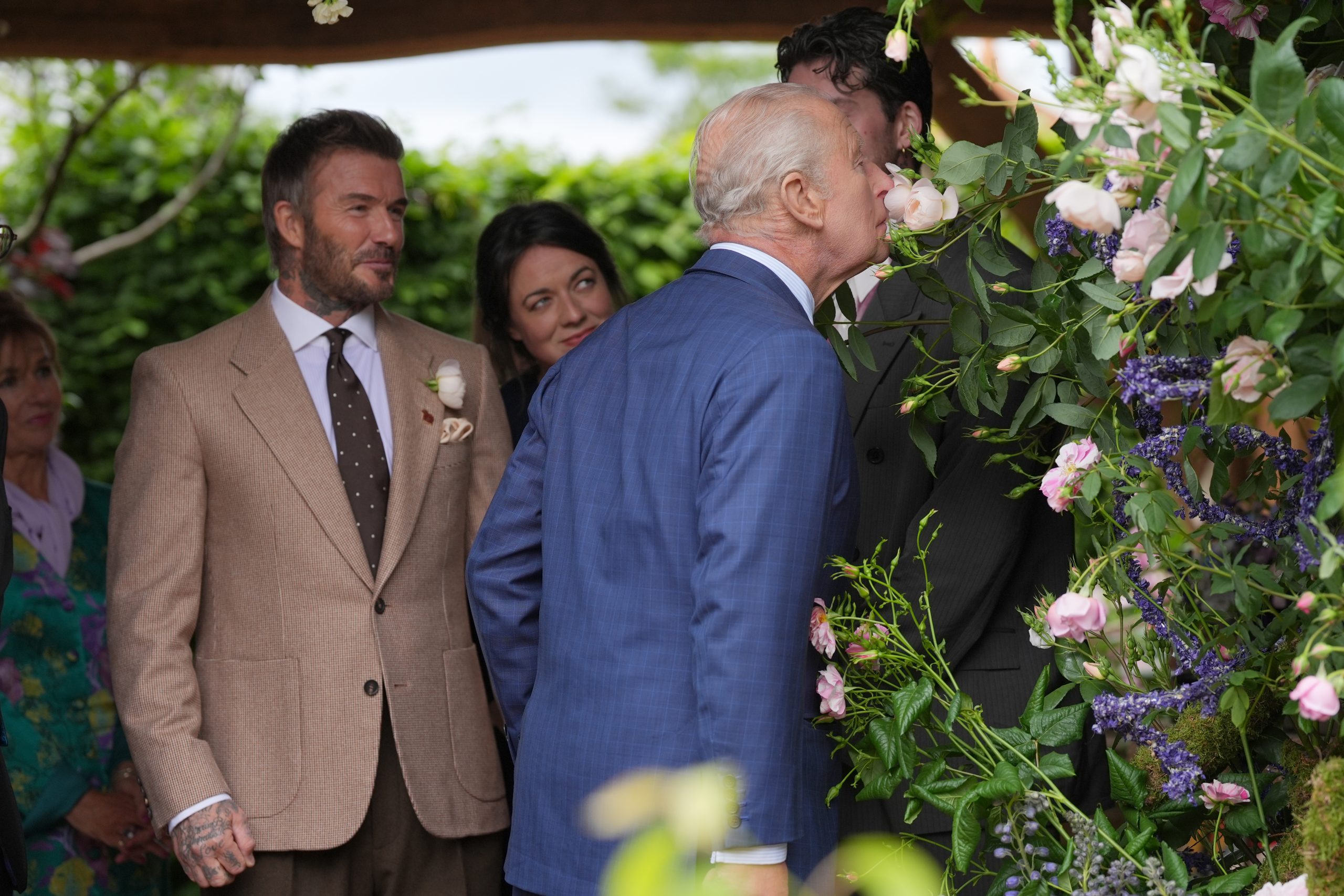 King Charles III smells a flower as Sir David Beckham looks on during his visit to the press day ahead of the 2026 RHS Chelsea Flower Show©&nbsp; Yui Mok - WPA Pool/Getty Images