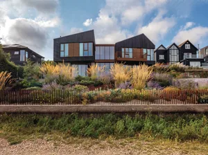Tall plumes of Stipa gigantea grass form a striking spectacle from the beach, whose grasses, wild alliums and sea kale inspired much of the planting here. House and garden are linked by the use of Corten steel in the detailing. Tall plumes of Stipa gigantea grass form a striking spectacle from the beach, whose grasses, wild alliums and sea kale inspired much of the planting here. House and garden are linked by the use of Corten steel in the detailing.
