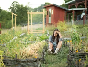 Young farmer woman feeling tired and stressed sitting in vegetable garden. Stock image Photo credit: Getty Images