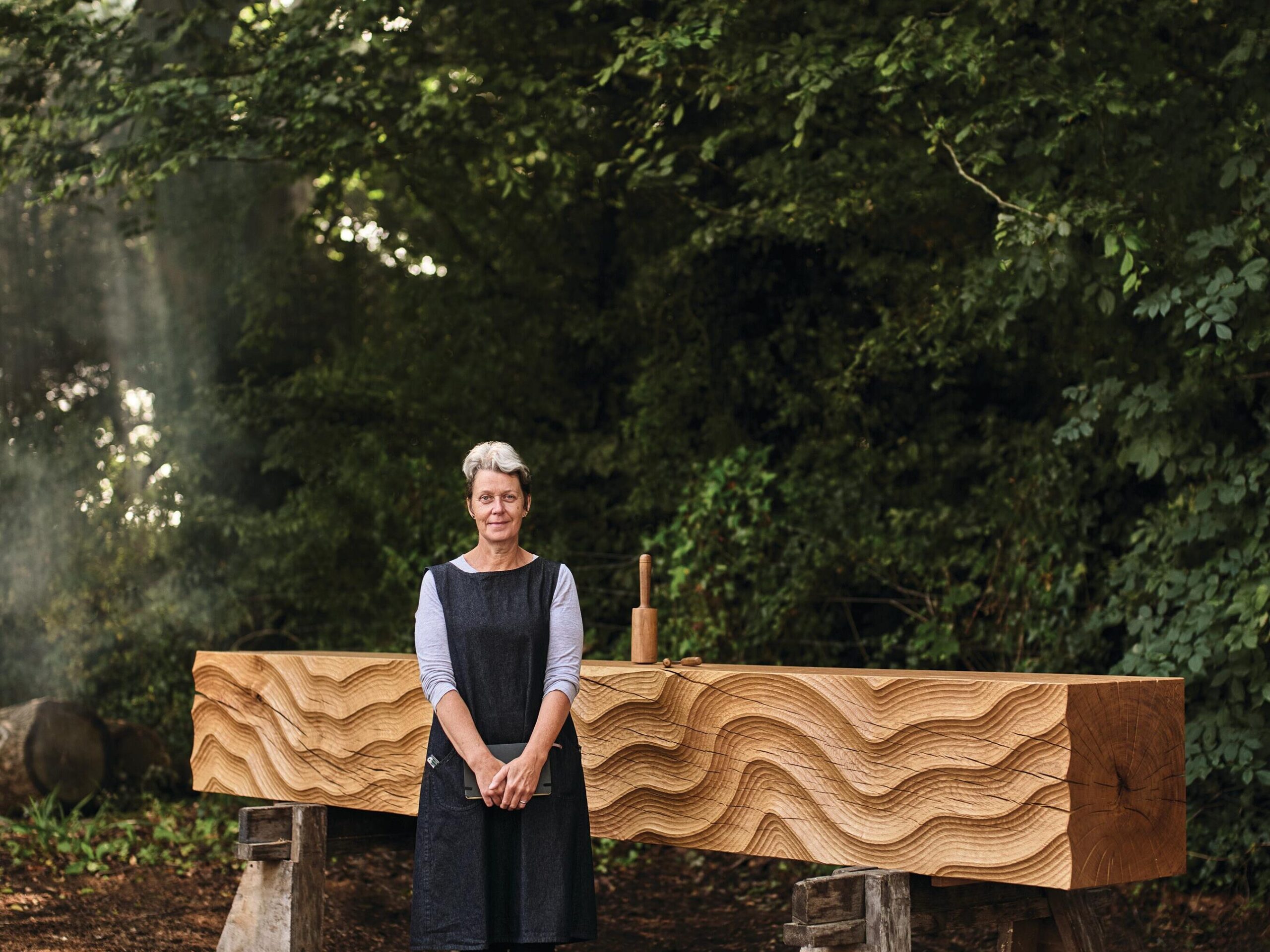 Woman stood next to wooden sculpture