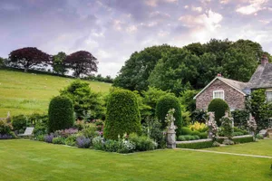 A series of oversized, clipped yews march out from the south-facing terrace and stand guard over the rose garden. Their outline is echoed in the trees beyond, helping to anchor the garden within its setting. A series of oversized, clipped yews march out from the south-facing terrace and stand guard over the rose garden. Their outline is echoed in the trees beyond, helping to anchor the garden within its setting.