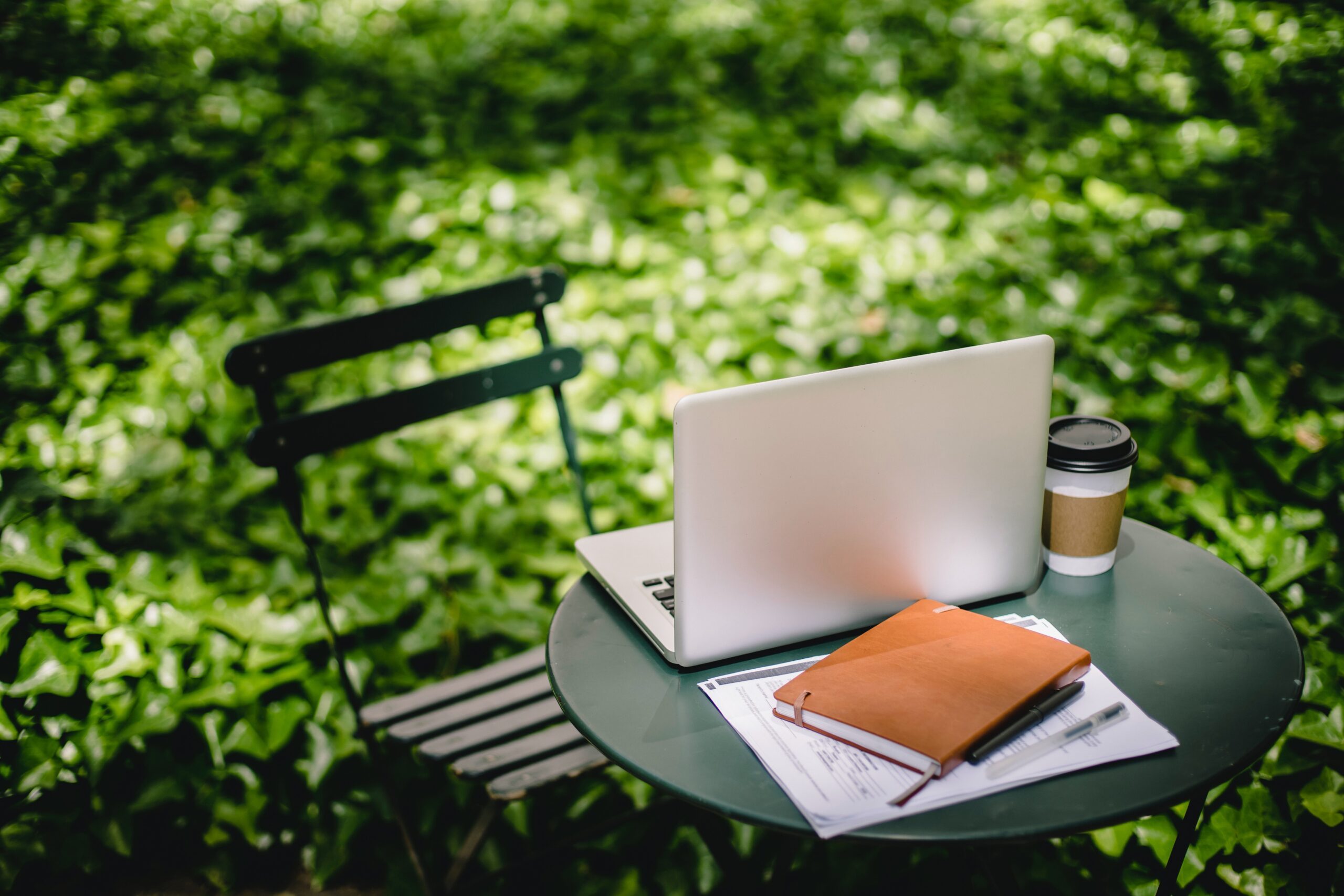 Laptop, coffee and notebook on a garden table