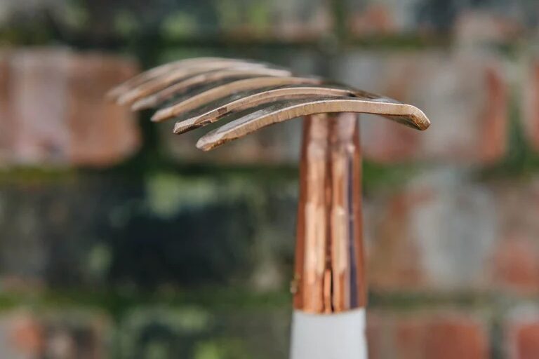 Atik Long Handled Mini Rake against a brick wall