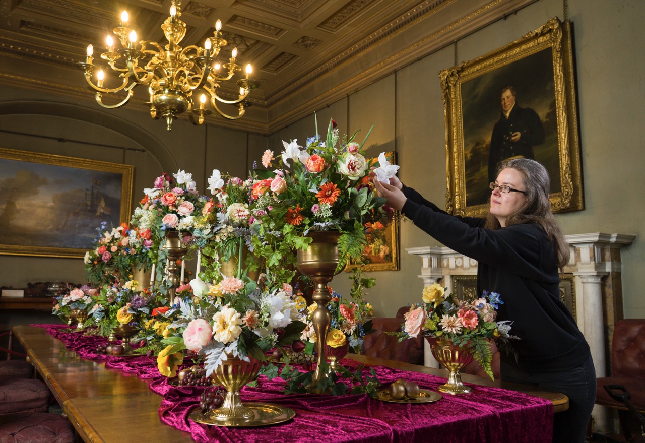 A person adjusting a floral display on a table