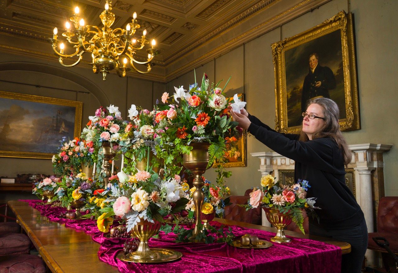 A person adjusting a floral display on a table