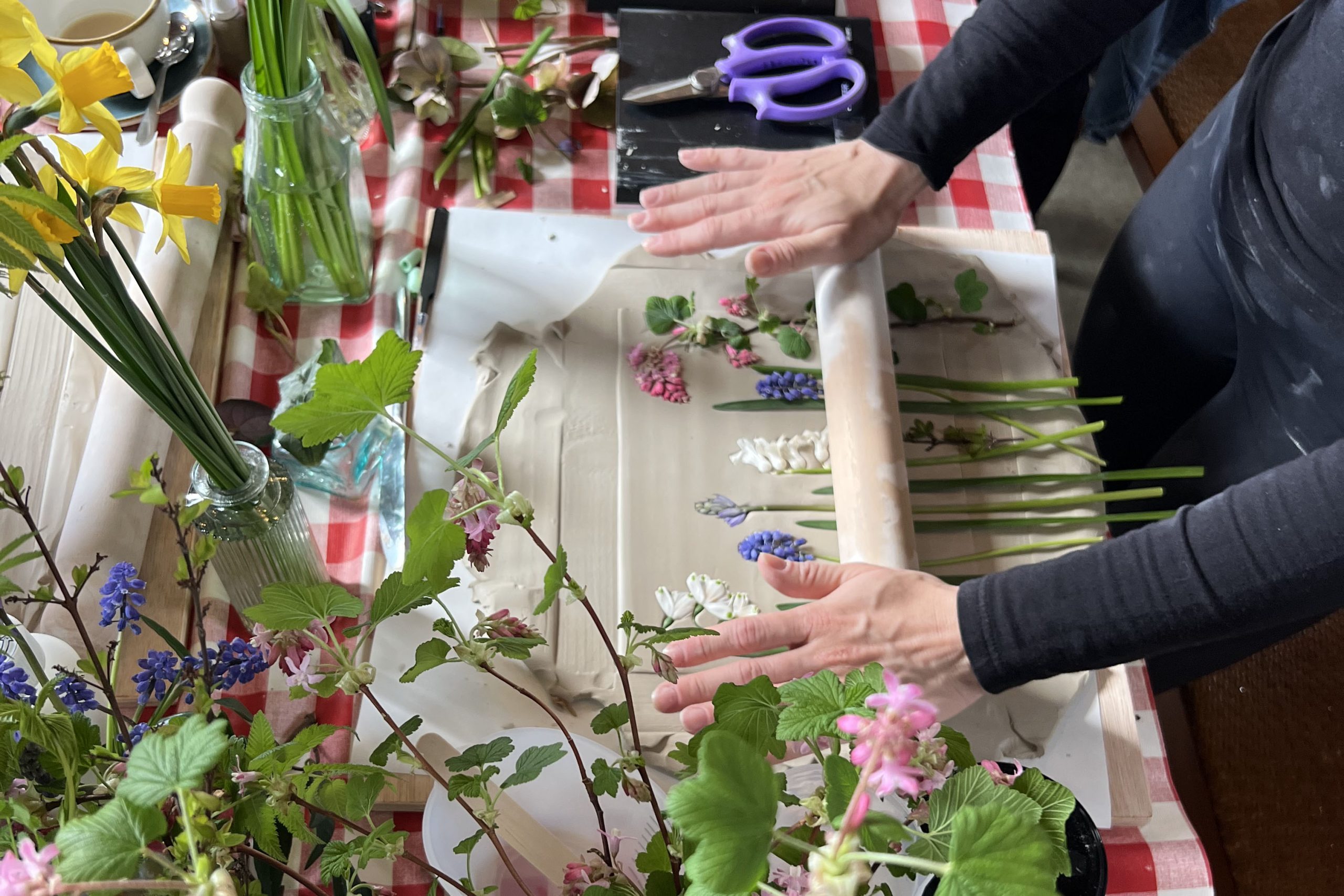 Rolling pressed flowers onto clay