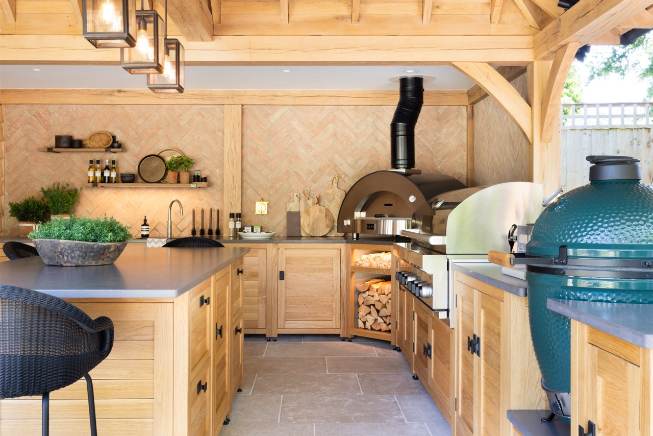 This outdoor kitchen at a Hampshire Beach House from Humphrey Munson includes a pizza oven and a Big Green Egg barbecue