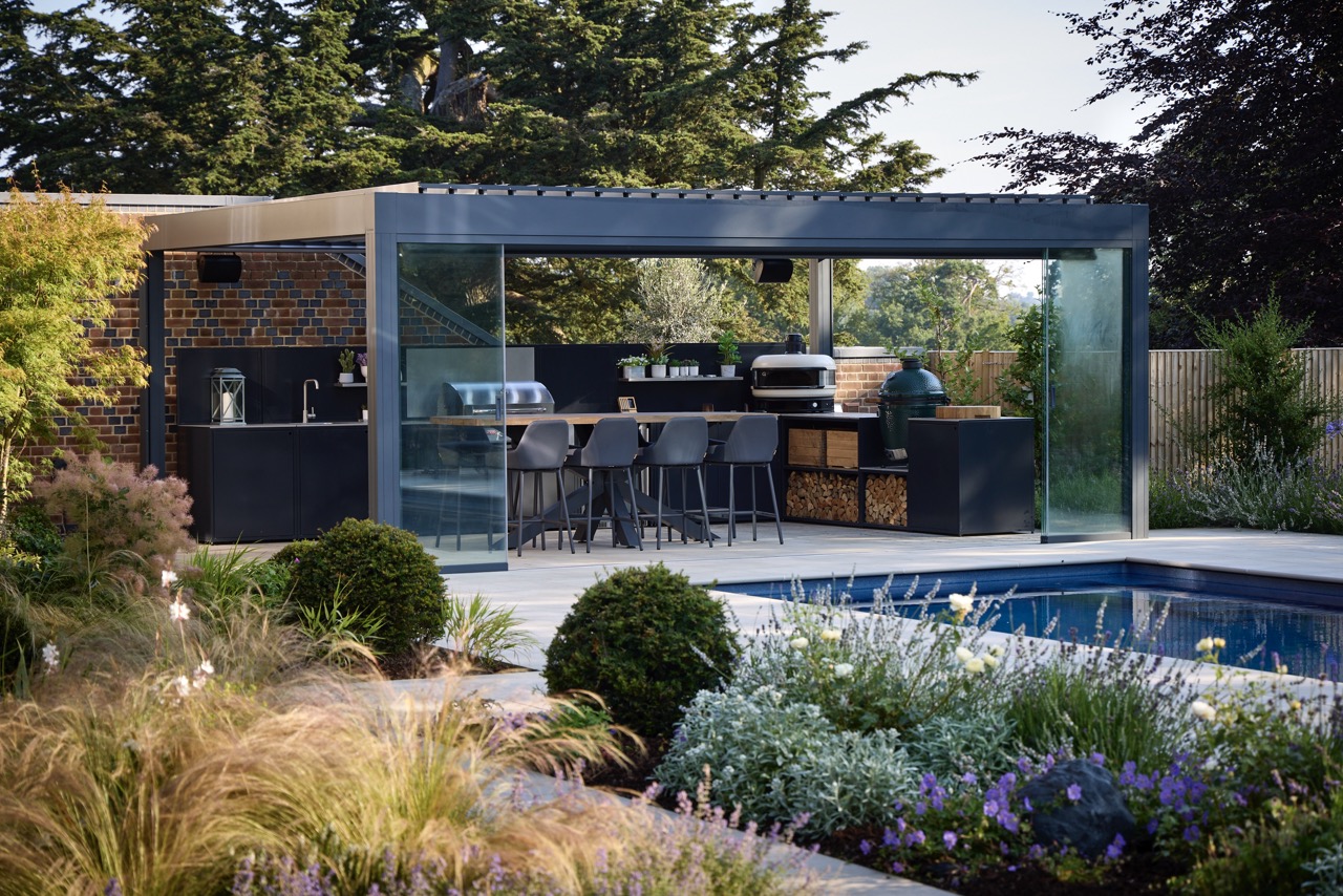 This sleek outdoor kitchen sits comfortably amongst thoughtful planting in the pool area