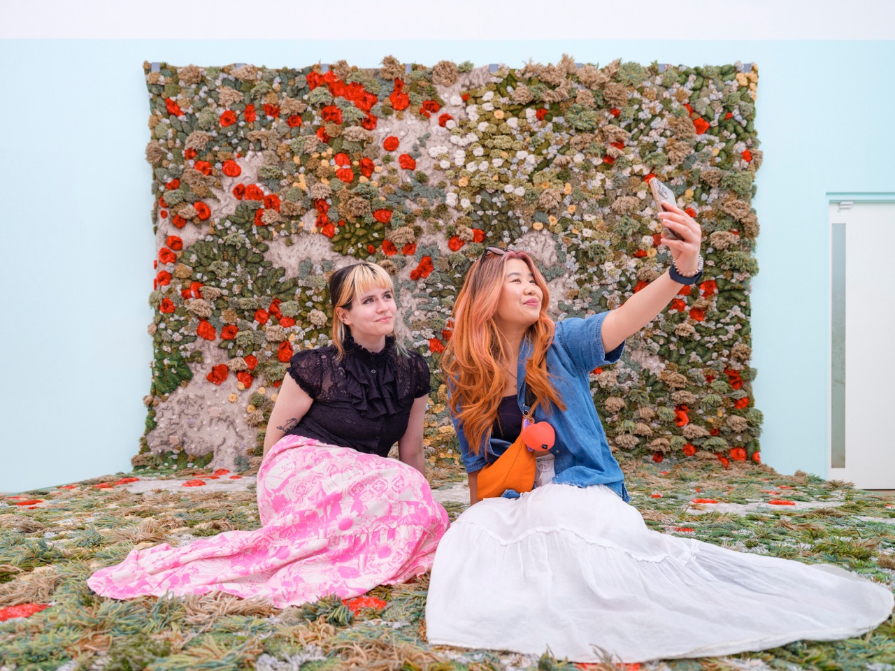 Two people sat in front of a flower wall exhibit