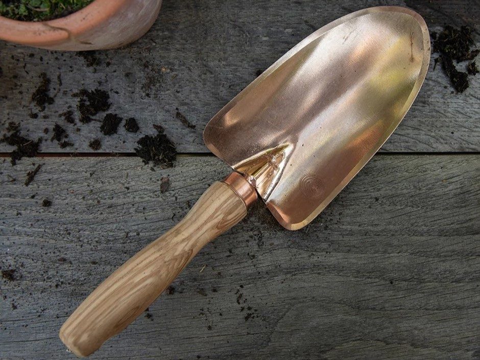Copper planting trowel on a wood table