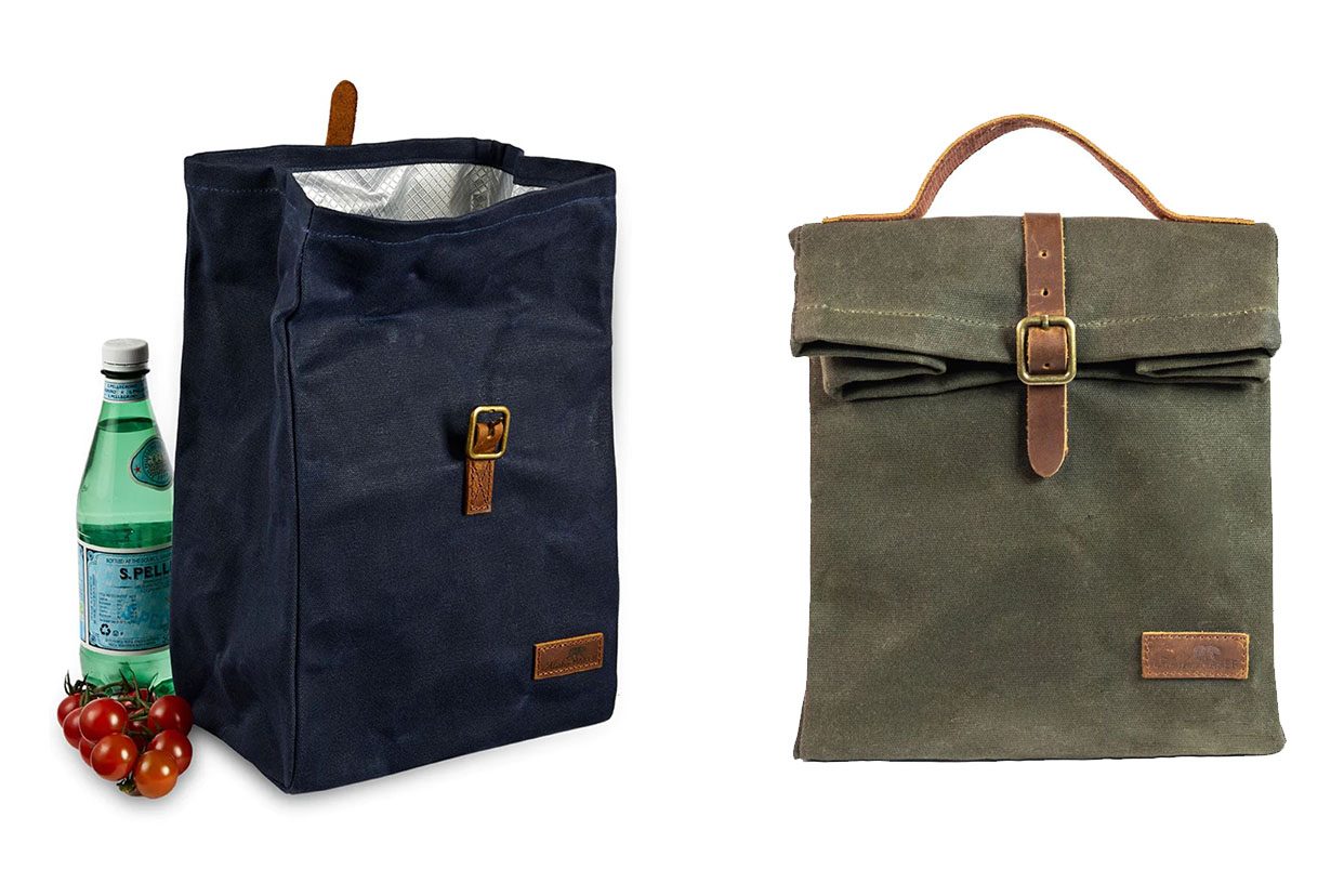 A navy and a green lunch bag with some water and tomatoes on a white background