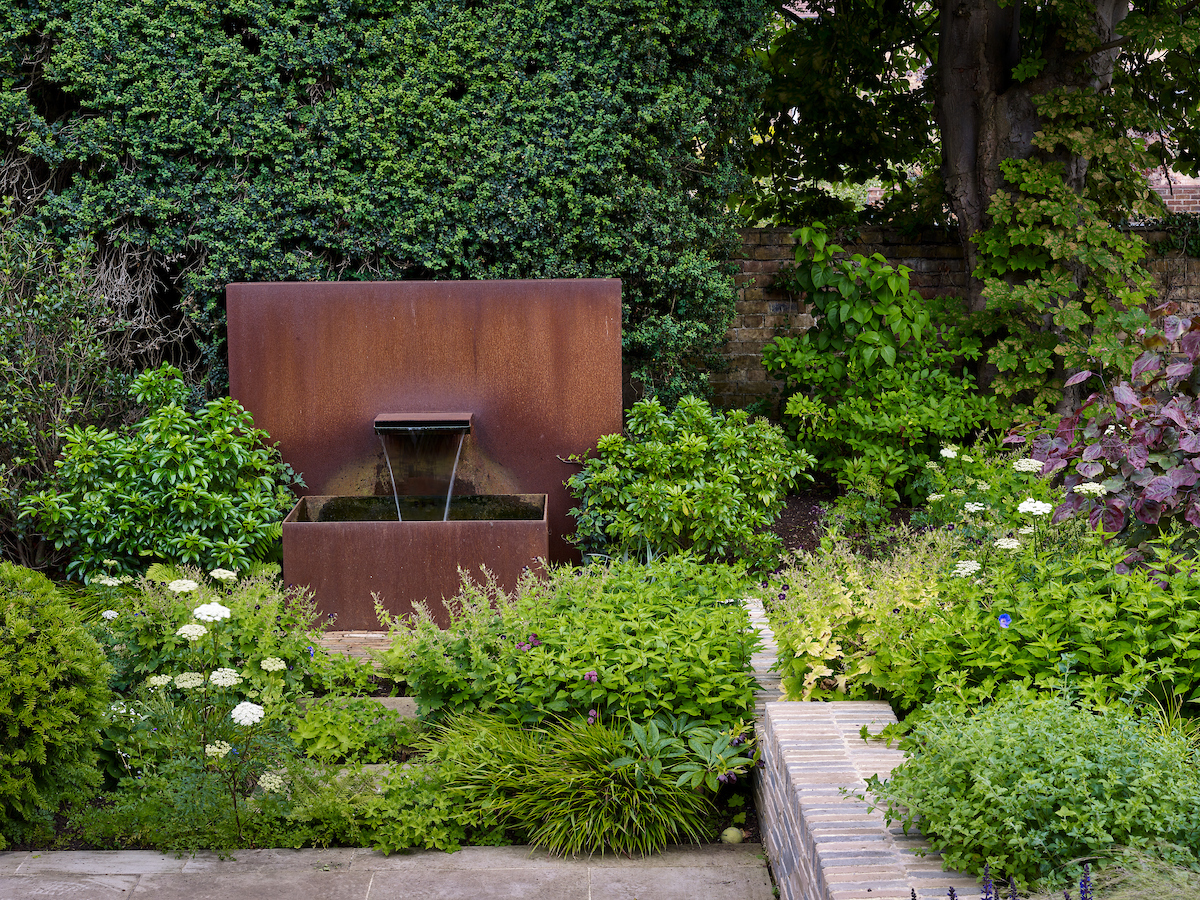 This contemporary water feature contrasts with lush planting in a private Oxford garden