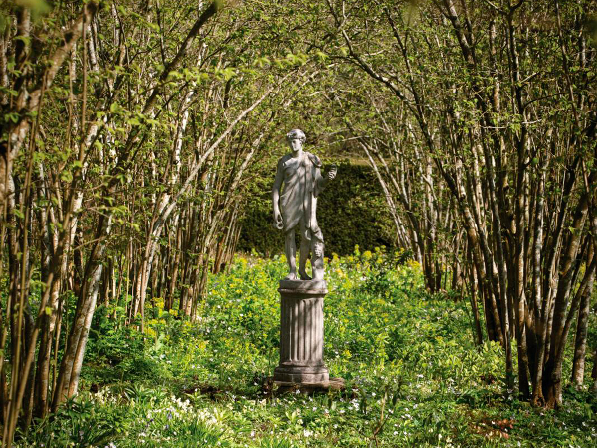 Arching branches and a centrally placed statue of Bacchus draw the eye in Sissinghurst’s Nuttery