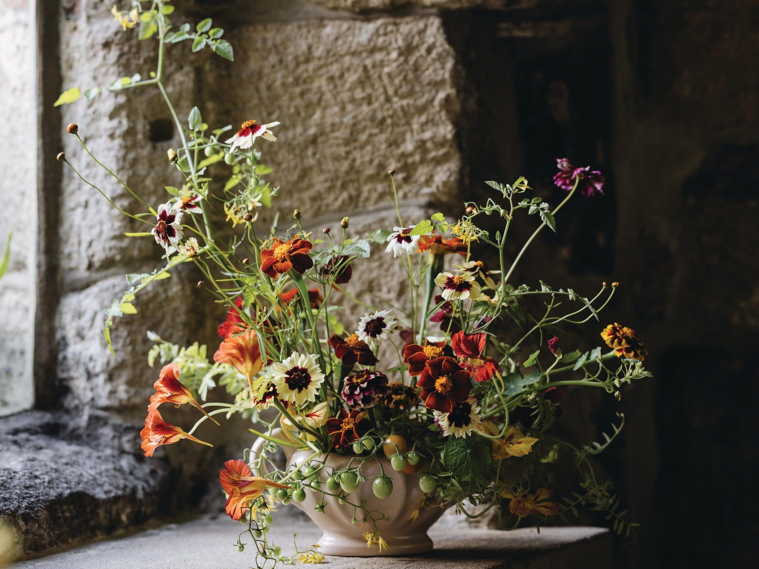 Flowers arranged in vessel by window