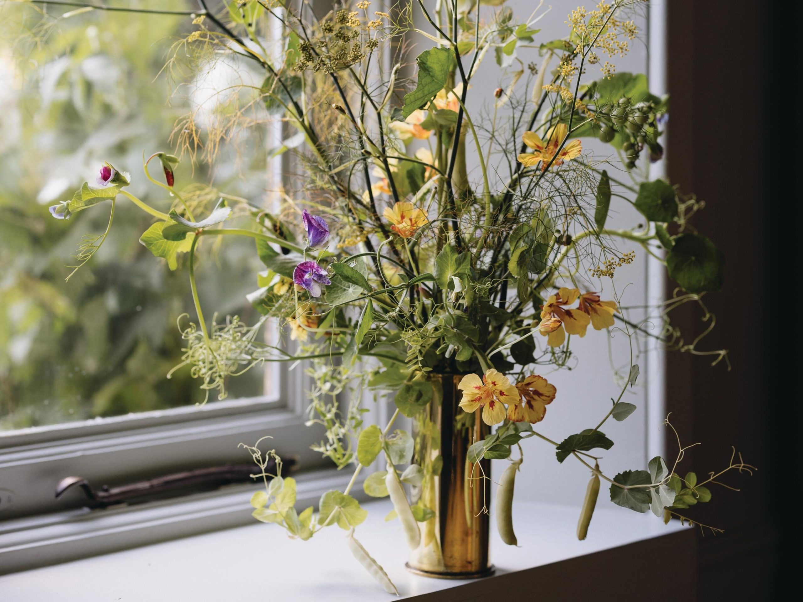 Flowers arranged in brass jug by window